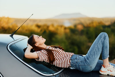 Low section of woman sitting on car