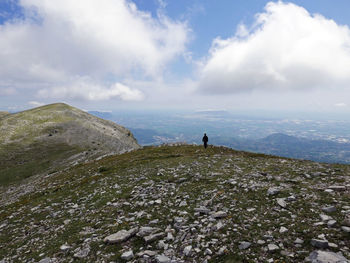 Rear view of man standing on mountain against sky