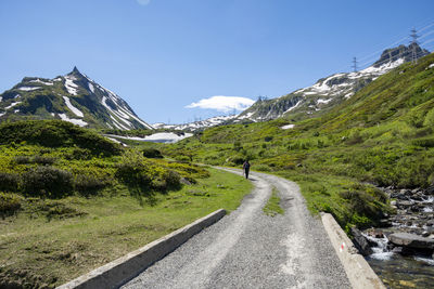 Road leading towards mountains against clear sky