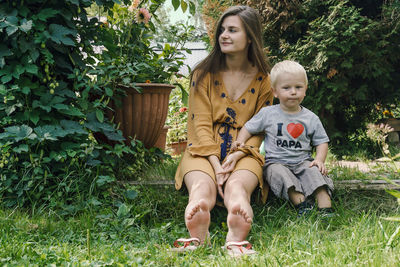 Smiling young woman sitting with cute son in park