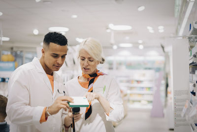 Colleagues checking medicine with bar code reader at pharmacy store