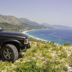 Scenic view of sea by mountains against sky