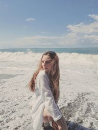 Beautiful young woman on beach against sky