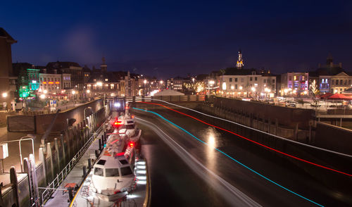 High angle view of light trails on road amidst buildings in city at night