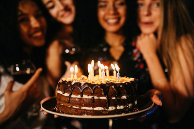 Women with birthday cake in darkroom