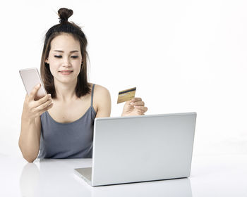 Young woman using smart phone against white background