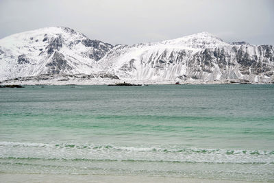 Scenic view of sea and snowcapped mountain against sky