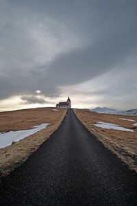 Empty road amidst land against sky