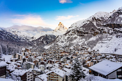 Aerial view of townscape and snowcapped mountain against sky