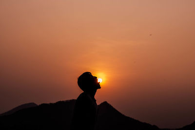 Optical illusion of man licking sun at sunset