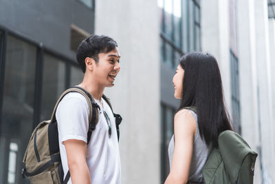 Side view of smiling couple standing against building