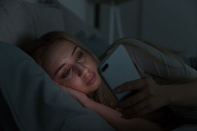 Close-up of woman using smart phone while lying on bed at home