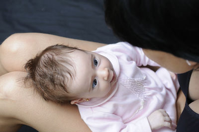 Cute baby girl relaxing on lap of mother