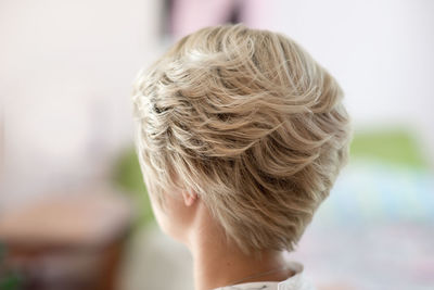 Rear view of woman with blond short hair at home