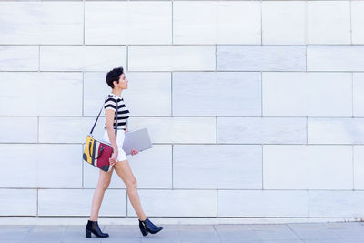 Portrait of young woman standing against wall