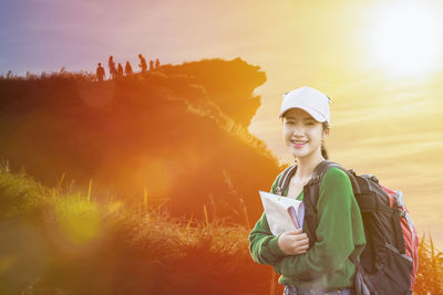 Portrait of smiling young woman standing against sky during sunset