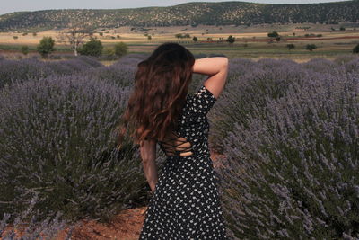 Rear view of woman standing by plants on land