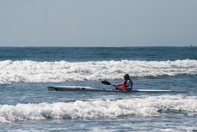 Man kayaking in sea against clear sky