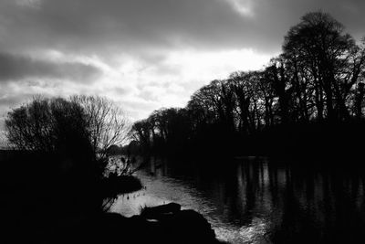 Silhouette trees by lake against sky during sunset