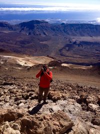 High angle view of man photographing while hiking on dramatic landscape