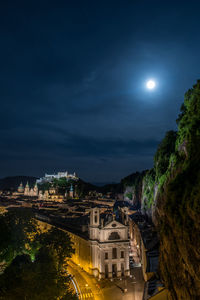 High angle view of buildings and mountain against sky at night