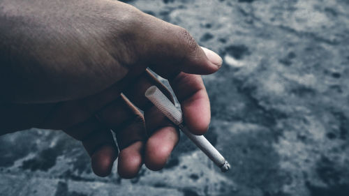 Close-up of hand holding cigarette