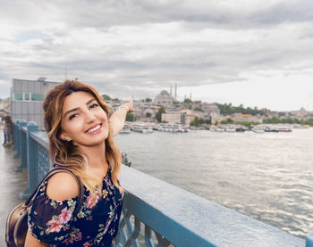 Portrait of smiling young woman against sky