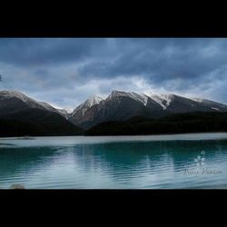 Scenic view of lake and mountains against cloudy sky