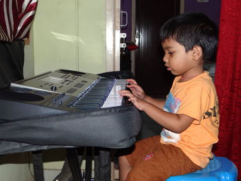 Side view of boy playing piano