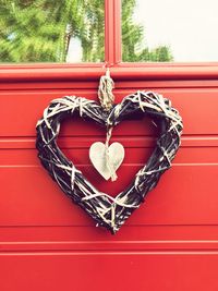 Close-up of red heart shape hanging on window