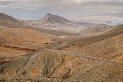 Scenic view of road by mountains against sky