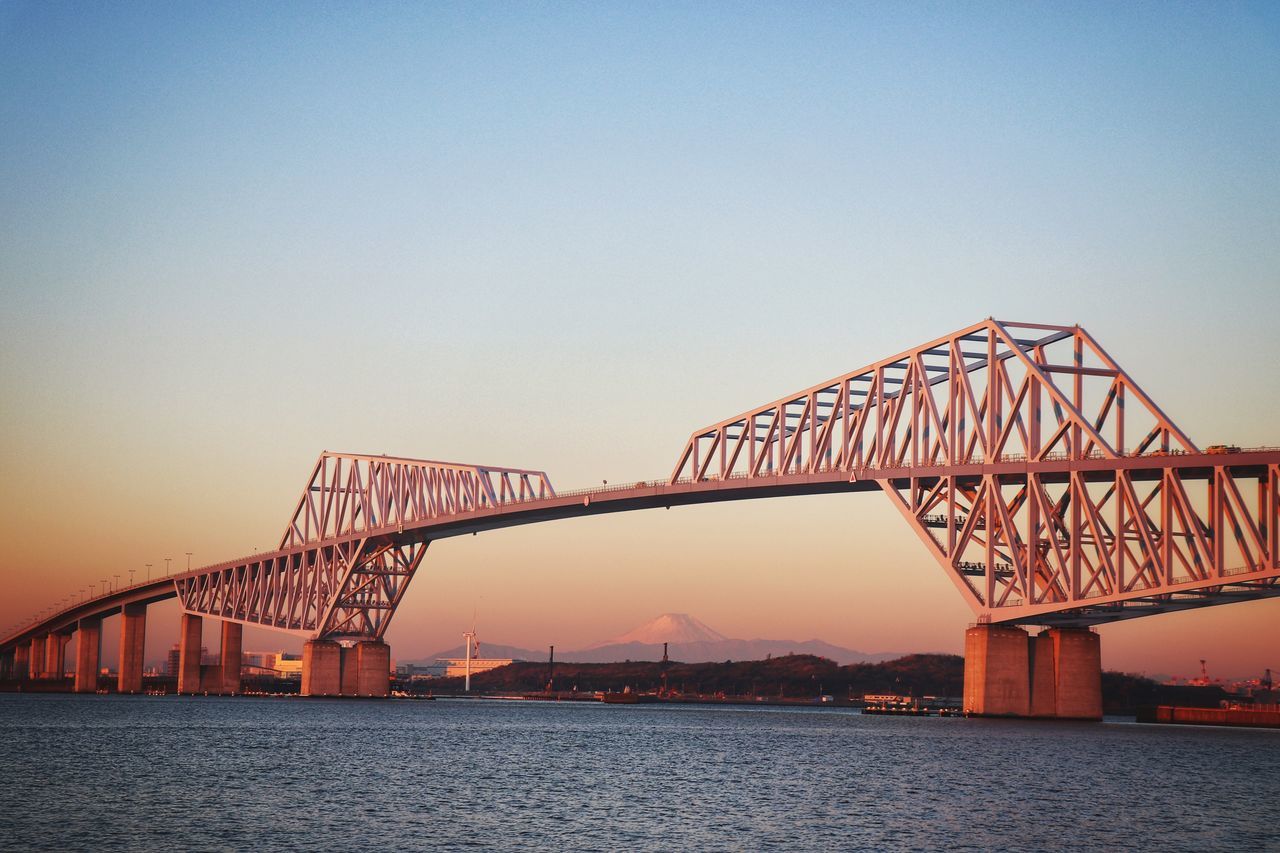 bridge - man made structure, connection, engineering, transportation, built structure, architecture, clear sky, copy space, travel, bridge, sunset, suspension bridge, river, water, sky, no people, outdoors, travel destinations, low angle view, city, day, nature