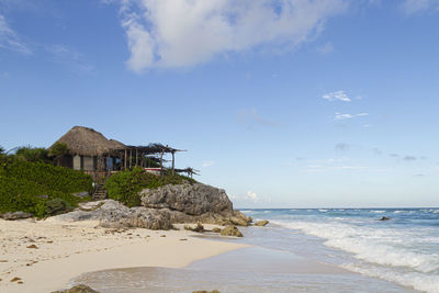 House on beach by sea against sky