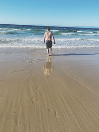 Rear view of woman on beach against sky