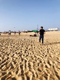 People playing on beach against clear sky