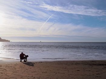 People at beach against sky during sunset