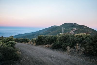 Road by mountain against sky during sunset