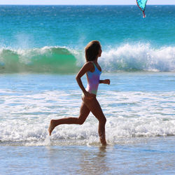 Side view of woman in swimwear running on shore