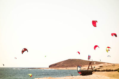 People paragliding on beach against clear sky