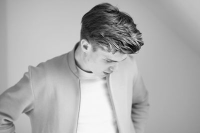 Sad young man looking down against white background