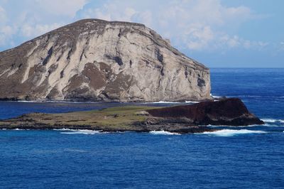 Scenic view of sea by rock formation against sky