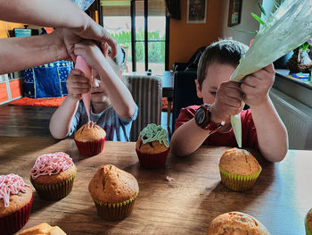 Cute kids decorating cupcakes at home