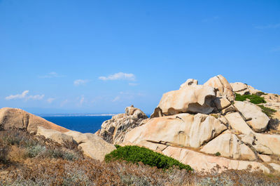 Rock formations by sea against blue sky