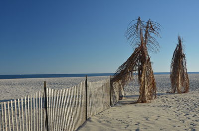 Fence on beach against clear sky