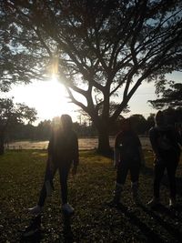 People standing by tree on field against sky