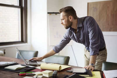 Man using laptop computer while standing in office