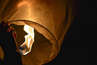 Cropped hand holding illuminated paper lantern at night