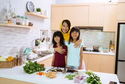 Portrait of smiling woman standing in kitchen at home