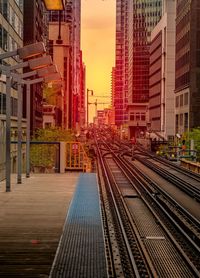 Railroad tracks in city against sky at sunset