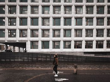 Rear view of woman walking on street against buildings in city